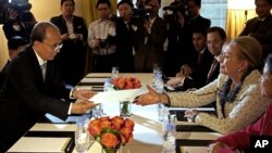 U.S. Secretary of State Hillary Rodham Clinton is handed an envelope from Burma's President Thein Sein as they meet in New York Sept. 26, 2012. 