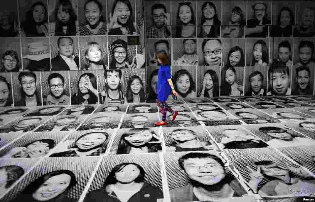 A woman walks through a display of portraits which were made as part of the Inside Out art project by French artist JR at Xintiandi area, in downtown Shanghai, China.