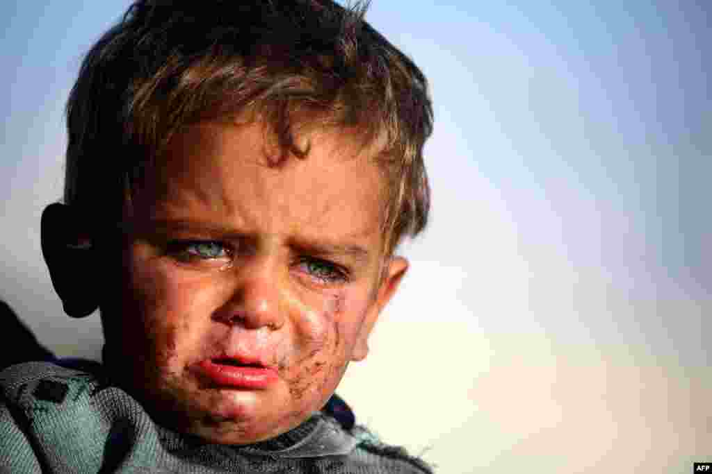 A Syrian boy cries as he is being held at a temporary refugee camp in the village of Ain Issa, housing people who fled Islamic State group's Syrian stronghold Raqa, some 50 kilometers (30 miles) north of the group's de facto capital, March 25, 2017.
