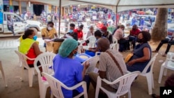 FILE - People wait to receive coronavirus vaccinations at a streetside vaccination tent in Kampala, Uganda, Sept. 7, 2021. Uganda is accelerating its vaccination drive and is now reaching out to people at bars and entertainment venues.