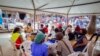 FILE - People wait to receive coronavirus vaccinations at a streetside vaccination tent in Kampala, Uganda, Sept. 7, 2021. Uganda is accelerating its vaccination drive and is now reaching out to people at bars and entertainment venues.