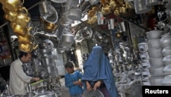 An Afghan woman carries a steel tray in a market at the old part of Kabul, May 9, 2012.