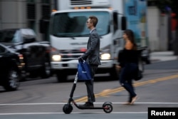 A man in a suit rides an electric BIRD rental scooter along a city street in San Diego, California, U.S. September 4, 2018. (REUTERS/Mike Blake)