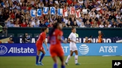 FILE - In this Aug. 29, 2019, file photo, fans hold up a sign for equal pay during the second half of an international friendly soccer match between the United States and Portugal in Philadelphia. The United States won 4-0. Last summer's Women's World Cup