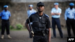 United Nations peacekeepers stand in the background as a Congolese national police officer holds a sword and stands with other officers during a gathering in Goma, in the Democratic Republic of Congo, December 2, 2012. 