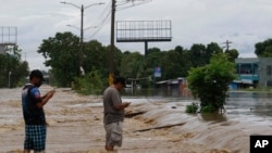 Warga mengambil gambar dengan telepon genggam mereka, suasana jalanan yang tergenang banjir akibat badai Iota yang melanda kawasan La Lima, Honduras, 18 November 2020. 