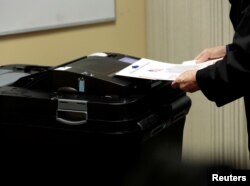 A voter places his ballot in a tabulating machine at the St. Paul Lutheran Church in East Lansing, Michigan, Nov. 6, 2018.
