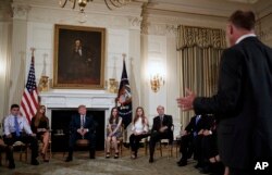 Marjory Stoneman Douglas High School students and parents and President Donald Trump look to Mark Barden, standing right, of Sandy Hook Promise and father of Sandy Hook shooting victim Daniel Barden, as he speaks during a session with high school students, teachers and others in the State Dining Room of the White House in Washington, Feb. 21, 2018.