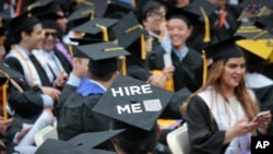 A graduating student wears a cap reading "hire me," as the City College of New York (CCNY) class of 2016 assemble for graduation, Friday June 3, 2016, in New York. First lady Michelle Obama delivered the keynote speech. (AP Photo/Bebeto Matthews)