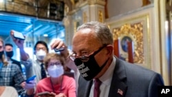 Senate Majority Leader Chuck Schumer of New York walks out of a Senate Democratic meeting pumping his fist, at the Capitol in Washington, Oct. 6, 2021, as a showdown loomed with Republicans over raising the debt limit.