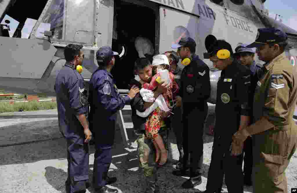 Uma criança ferida é transportada por um soldado nepalês depois de ser evacuada num helicóptero da Força Aérea Indiana no aeroporto de Katmandu, Nepal, Abril 27, 2015.