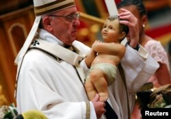 Pope Francis holds a statuette of baby Jesus during the traditional midnight mass in St. Peter's Basilica on Christmas Eve at the Vatican, Dec. 24, 2017.