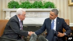 President Barack Obama (r) shakes hands with Palestinian President Mahmoud Abbas during their meeting in the Oval Office of the White House, March 17, 2014.