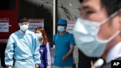 Hospital workers and visitors wearing masks pass by a precaution against the MERS, Middle East Respiratory Syndrome, virus at a quarantine tent for people who could be infected with the MERS virus at Seoul National University Hospital in Seoul, South Kore
