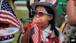FILE - Eight year old Hana Cho from Girl Scout Troop 5665 tests out a horn prior to participating the 4th of July parade in Santa Monica, Calif. on Tuesday, July 4, 2017.