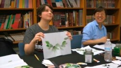 Mahasiswa sarjana Moe Lewis, kiri, menunjukkan lukisan cat air daun peony di kelas melukis tradisional China di Institut Konfusius di Universitas George Mason di Fairfax, 2 Mei 2018. (Foto: AP)