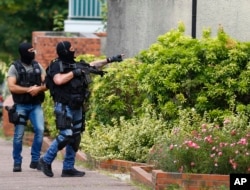 Hooded police officers conduct a search in Saint-Etienne-du-Rouvray, Normandy, France, following an attack on a church that left a priest dead, July 26, 2016.