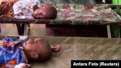 FILE - Two sick children wait for treatment after being admitTed to a hospital in Agats, Asmat District, after the government dispatched military and medical personnel to the remote region of Papua to combat malnutrition and measles, Indonesia, Jan. 22, 2018. 