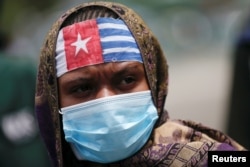 Seorang aktivis Papua yang mengenakan bandana dan masker ikut protes menuntut referendum. (Foto: Reuters)