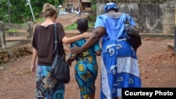 Cora, a trafficking survivor, walks with her case manager and social worker in Sierra Leone. Credit: WHI