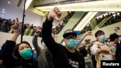Protesters give thumbs-down signs to mainland Chinese travelers during a demonstration inside a shopping mall in Hong Kong, Feb. 15, 2015.