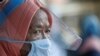 Seorang perempuan menggunakan pelindung wajah dan masker di sebuah stasiun seiring dengan pelonggaran pembatasan sosial di tengah pandemi virus corona (Covid-19) di Jakarta, 8 Juni 2020. (Foto: Reuters)