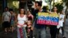 Un migrante venezolano lleva un cartel mientras camina hacia una manifestación en apoyo a Juan Guaidó, en Montevideo, Uruguay, el jueves 7 de febrero de 2019.