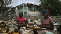 Women sell fruits and vegetables in front of a damaged house in Jacmel, Haiti, after the earthquake in January. The Global Heritage Fund says Jacmel is one of the world’s last historic cities of steel and iron architecture.