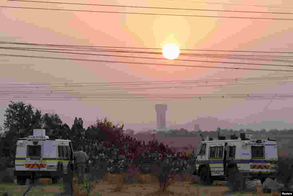 Police keep watch as striking miners gather outside the mine in Rustenburg, August 15, 2012.