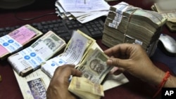 An employee counts Indian rupee notes at a bank in Allahabad, India, May 16, 2012.