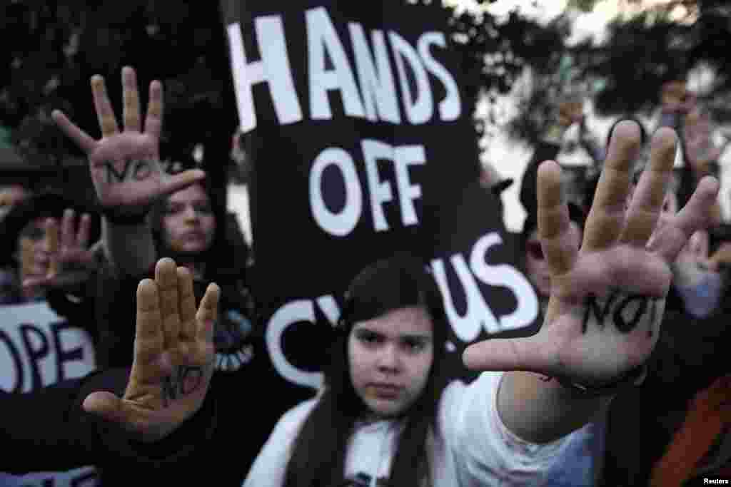 Protesters raise their open palms showing the word &quot;No&quot; during an anti-bailout rally outside the parliament in Nicosia, Cyprus. Cypriot ministers were trying to revise a plan to seize money from bank deposits before a parliamentary vote on Tuesday that will secure the island&#39;s financial rescue.