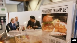 A photo showing U.S. President Donald Trump, left, and Japanese Prime Minister Shinzo Abe, right, at a lunch of hamburgers from Munch's Burger Shack is on display at the restaurant in Tokyo Thursday, Nov. 16, 2017. (AP Photo/Eugene Hoshiko)