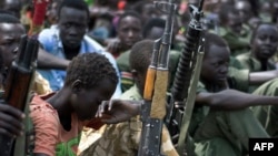 FILE - Boys with their rifles sit at a ceremony of child soldier disarmament, demobilization and reintegration in Pibor, Jonglei state, South Sudan, overseen by UNICEF and partners, Feb. 10, 2015.
