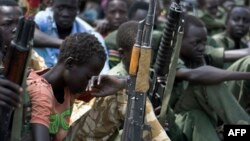 Anak-anak laki-laki dengan senapannya dalam upacara pelucutan, demobilisasi dan integrasi kembali tentara anak-anak di Pibor, Sudan Selatan (10/2). (AFP/Charles Lomodong)