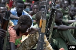 Boys with their rifles sit at a ceremony for child soldier disarmament, demobilization and reintegration in Pibor, Jonglei State, South Sudan, oversawn by UNICEF and partners, Feb. 10, 2015.