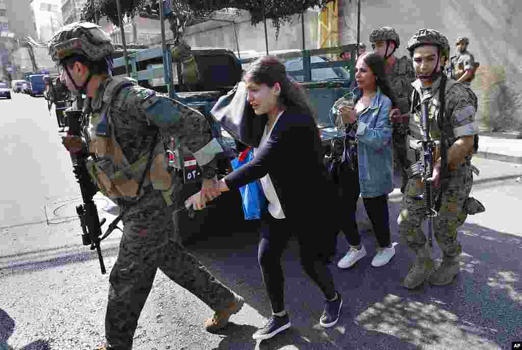 Lebanese army special forces soldiers assist teachers as they flee their school after deadly fighting broke out nearby along a former 1975-90 civil war front-line between Muslim Shiite and Christian areas at Ain el-Remaneh neighborhood, in Beirut, Lebanon.
