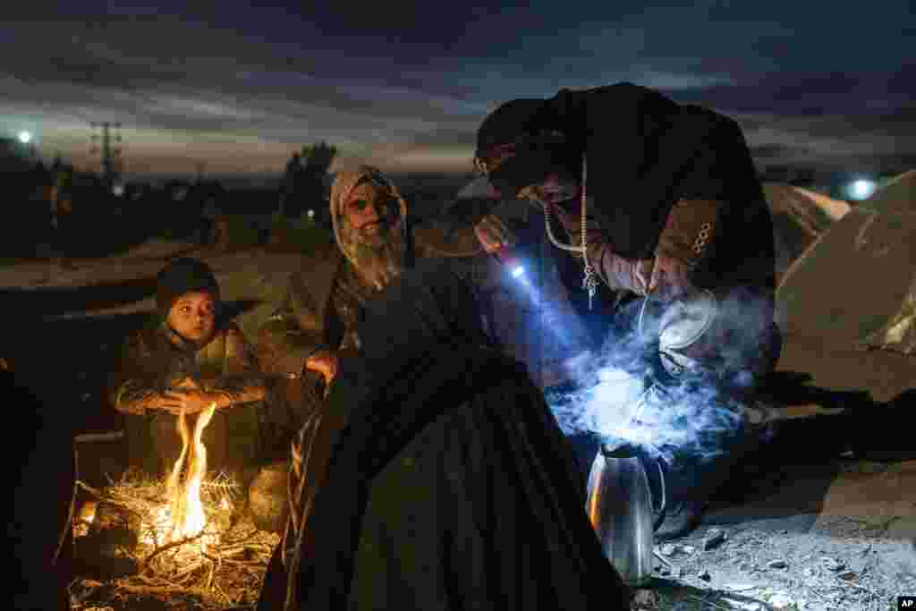 A family prepares tea outside the Directorate of Disaster office where they are camped, in Herat, Afghanistan.