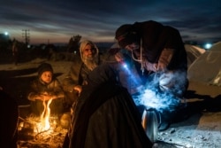 ہرات، افغانستان میں کھلے آسمان کے نیچے آگ جلا کر بیٹھا خاندان ۔ 29نومبر 2021