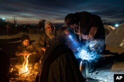 ہرات، افغانستان میں کھلے آسمان کے نیچے آگ جلا کر بیٹھا خاندان ۔ 29نومبر 2021