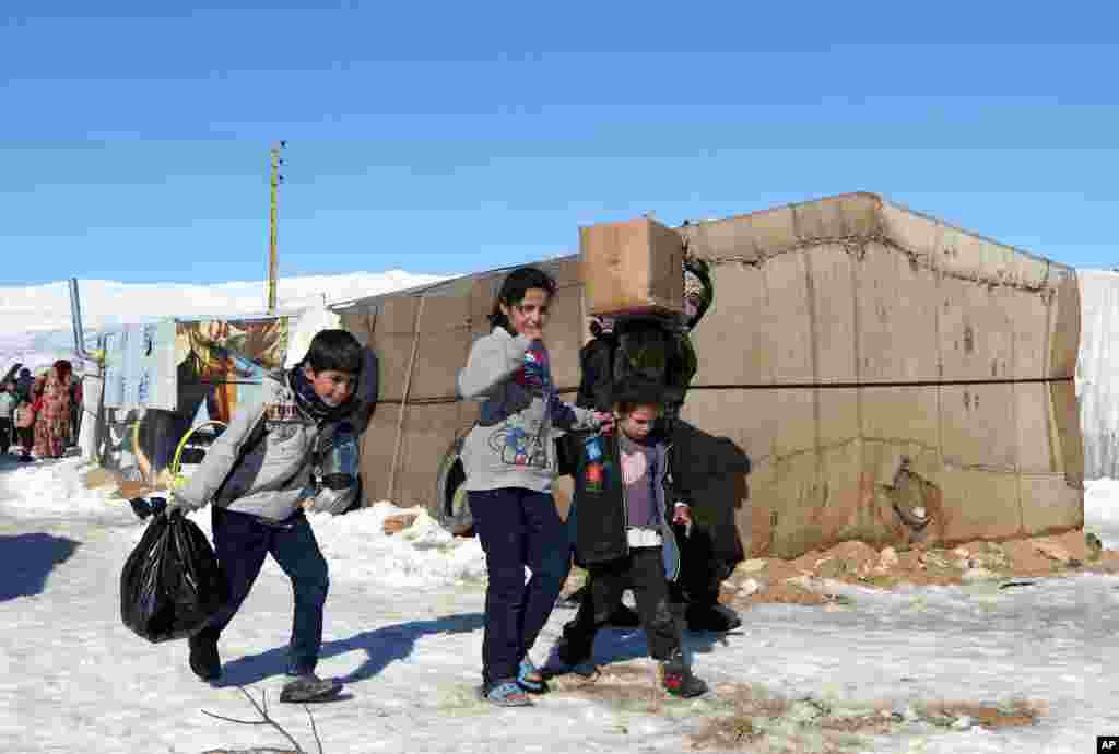 Syrian refugees carry aid donated by the local municipality near the ancient Roman city of Baalbek in eastern Lebanon, Dec. 15, 2013.