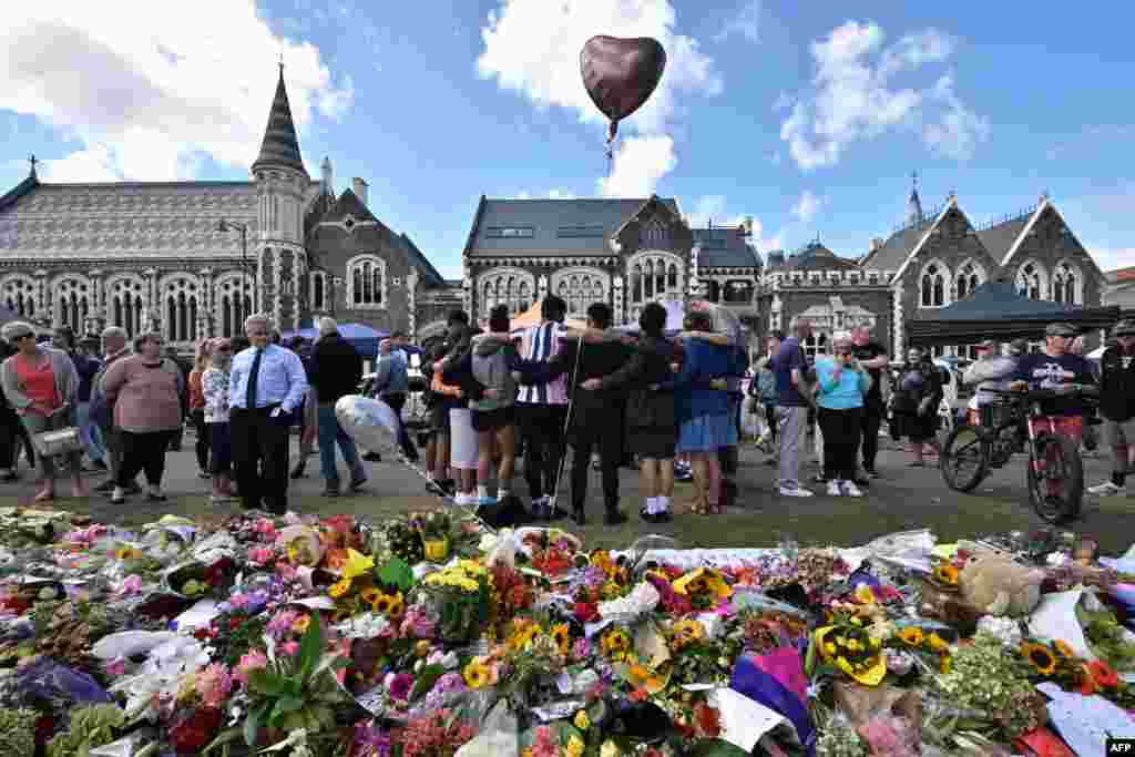 A group of students sing in front of flowers left in memory of victims of a shooting at two mosques in Christchurch, New Zealand.&nbsp; &nbsp;