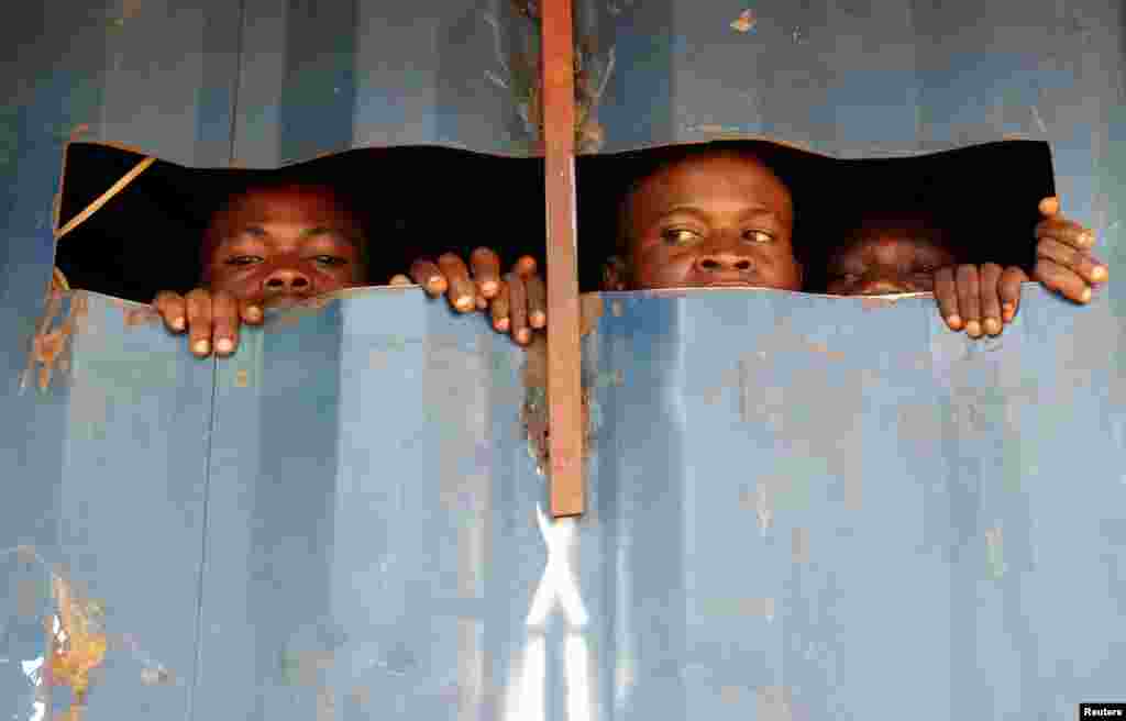 Detained Mai-Mai Yakutumba rebels, captured by Congolese soldiers from the Armed Forces of the Democratic Republic of Congo (FARDC) look out of a container in Namoya, Maniema Province, eastern Democratic Republic of Congo.