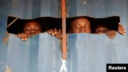 FILE - Detained Mai Mai Yakutumba rebels, captured by soldiers from the Armed Forces of the Democratic Republic of the Congo (FARDC), look out of a container in Namoya, Maniema province, eastern DRC, April 26, 2018. Members of an affiliated militia attacked trucks belonging to Banro Corp.'s Namoya gold mine this week, the army said.