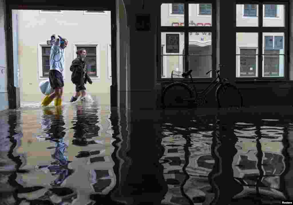 A couple walk through a flooded street past a flooded hallway of a house near the Elbe river in the east German town of Pirna, June 4, 2013. 