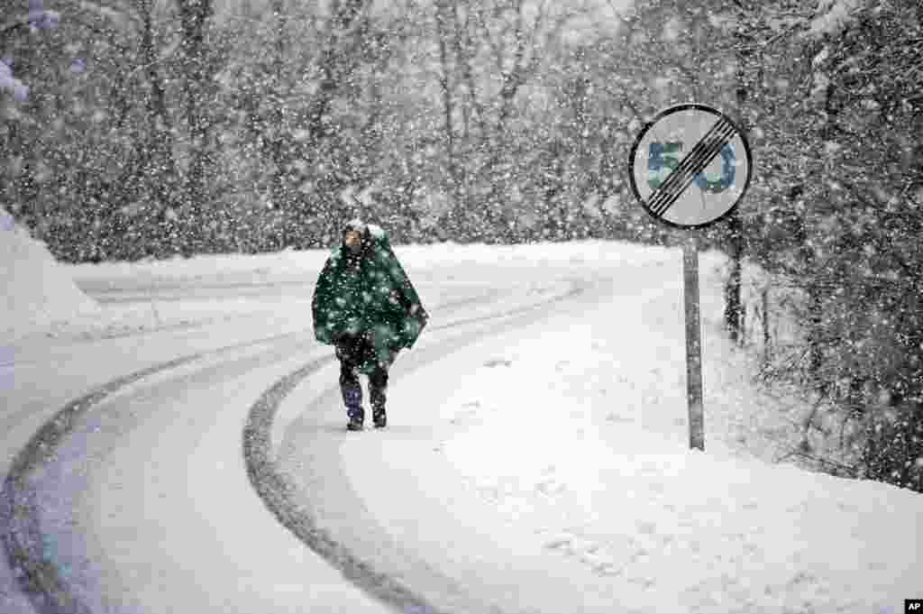 Antonio Lazza, a 60 year old pilgrim from Italy, walks alongside the road of Saint James&#39;s Way during a snow fall on a Spring morning near the Pyrenees town of Erro, northern Spain. The Saint James Way is a pilgrimage route ending in Santiago de Compostela that attracts people from all over the World.