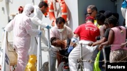 A woman is helped by medical staff abroad the Italian Navy vessel Vega at the Reggio Calabria harbor, southern Italy, May 29, 2016. 