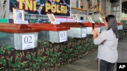 A relative uses her phone to take photos of the coffins containing the bodies of the victims of separatist attack in Nduga district, at Moses Kilangin Airport in Timika, Papua province, Indonesia, Dec. 7, 2018. 