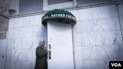 A woman stands below the awning of an Ahmadi mosque in Brooklyn, New York. “Love for all, hatred for none,” the banner reads. (R. Taylor/VOA)