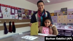一名土耳其婦女帶同她的六歲女兒參加星期天舉行議會選舉投票。