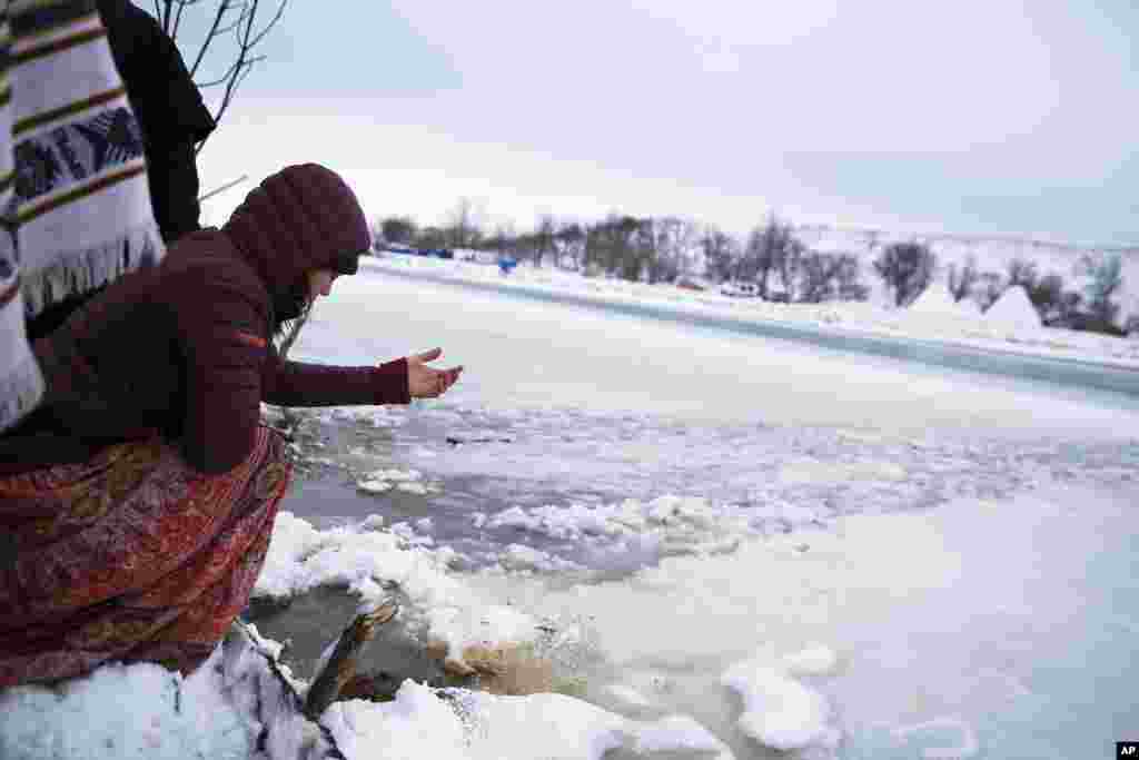 Megan Toben releases tobacco at the edge of the Cannonball River during a Native American water ceremony at the Oceti Sakowin camp where people have gathered to protest the Dakota Access oil pipeline in Cannon Ball, North Dakota.&nbsp; According to Native American beliefs, tobacco is used to open a barrier between the physical and the spiritual worlds.